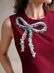 Maroon sleeveless mini dress close-up: silver sequined bow with dangling tassels