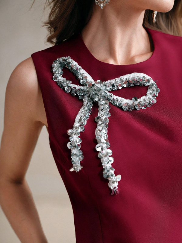 Maroon sleeveless mini dress close-up: silver sequined bow with dangling tassels