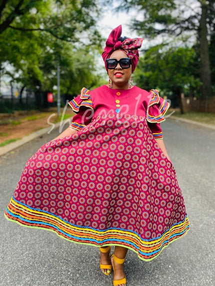Pink traditional dress with ruffle sleeves, circle pattern, and multicolor striped hem