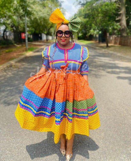 Geometric tiered dress with matching yellow headwrap, multicolor blue orange patterns.