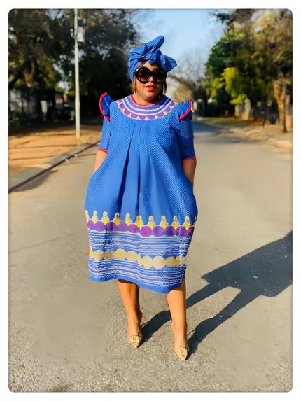 Blue traditional dress with scalloped edge motif, short sleeves, round neckline, colorful hem trim