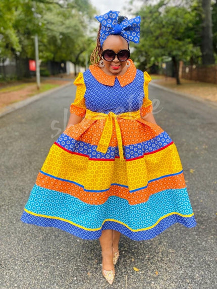 Tiered ruffle midi dress set with blue headwrap, orange and yellow patterned fabric.