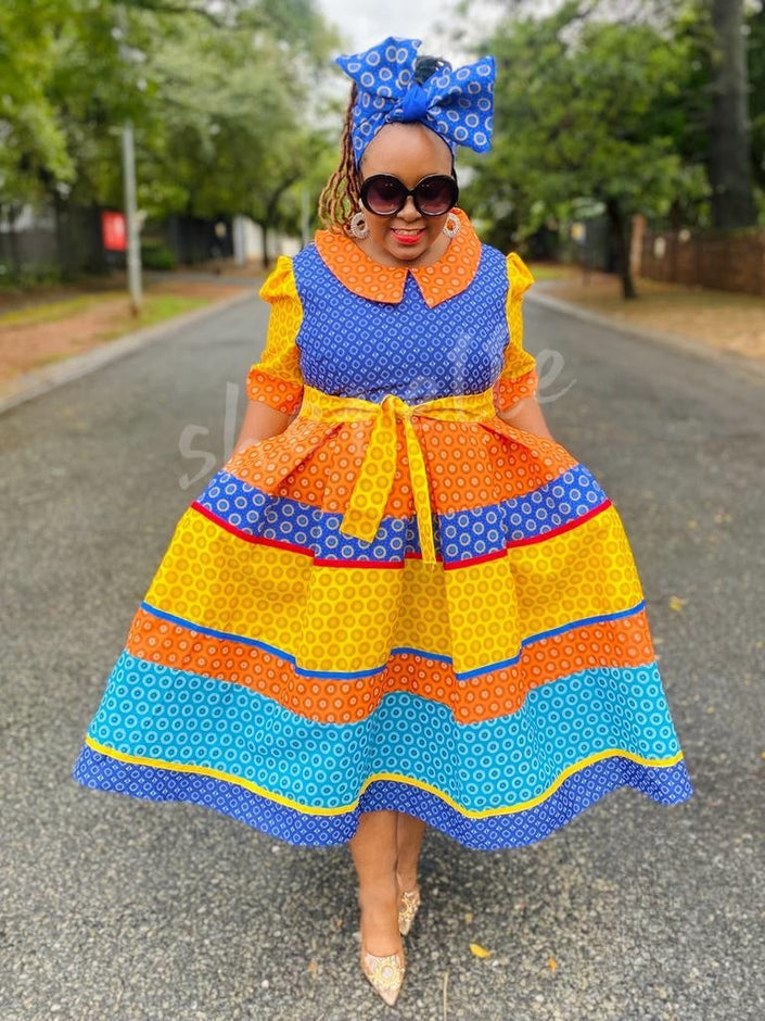 Tiered ruffle midi dress set with blue headwrap, orange and yellow patterned fabric.