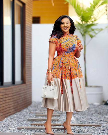 Pleated midi dress with embellished neckline, orange print and blue accents, short sleeves.