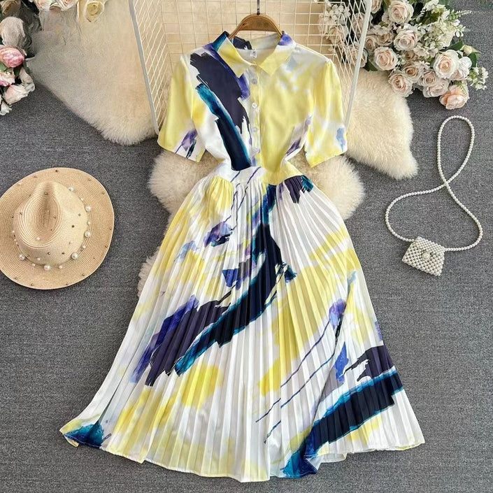 Pleated midi shirt dress with yellow base and blue abstract print, button front, short sleeves