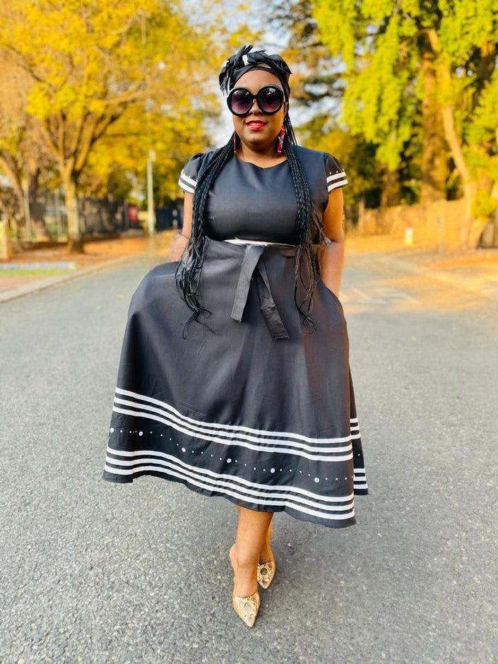 Black midi dress with ruffle sleeves, striped hem band, and tied waist sash