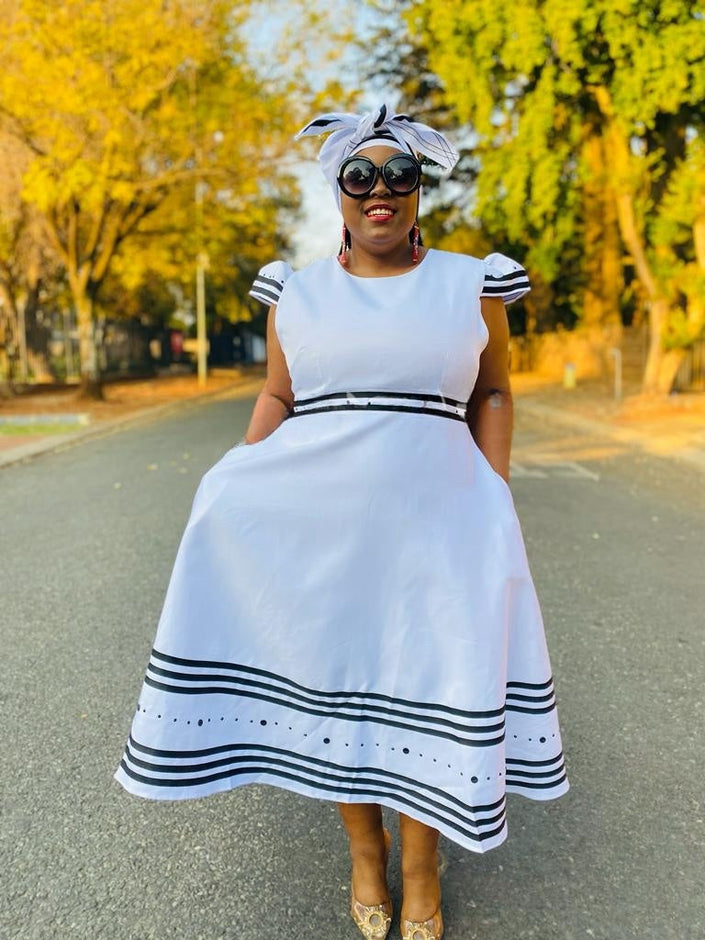 White midi dress with ruffle sleeves, striped hem bands, and tied waist sash