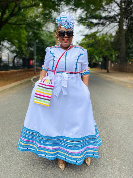 White geometric beaded midi dress with blue and pink striped hem and button accents