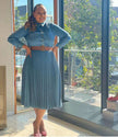Blue denim midi dress with pleated high-waist skirt, long sleeves, button front.