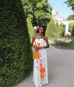 White strapless maxi dress with bold floral print, pleated bodice and flowing skirt