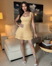 Tan sleeveless pleated mini dress with tiered ruffle skirt and square neckline