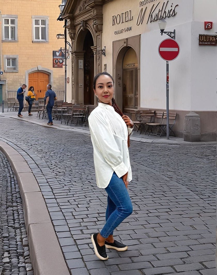 White long-sleeve pleated blouse with vertical pintucks and loose cuffs