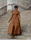 Brown maxi dress with long sleeves, high neckline, and gathered A-line skirt