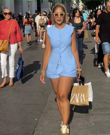 Sleeveless front-tie romper in light blue with buttoned bodice and tied waist detail