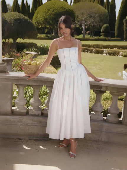 White midi dress with thin straps, fitted bodice, and flared mid-length skirt