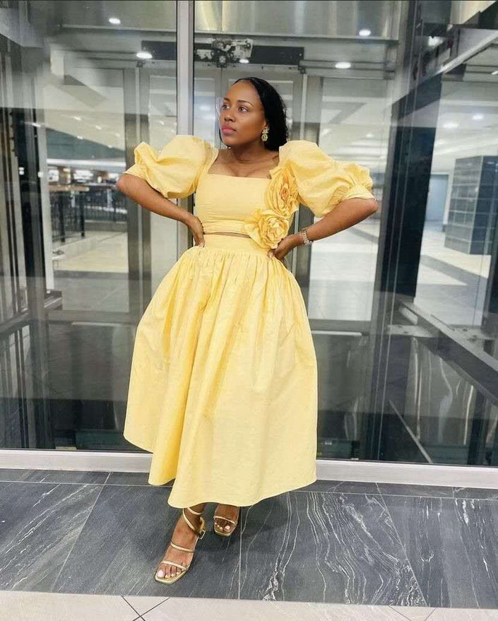 Yellow midi dress with puff sleeves, square neckline, floral applique at waist.