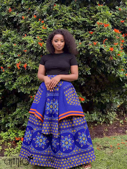 Blue African print maxi skirt with floral motifs and orange trim, full gathered flare.