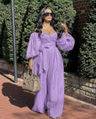 Light-purple off-shoulder jumpsuit with puff sleeves, ruched bodice, and wide-leg pants