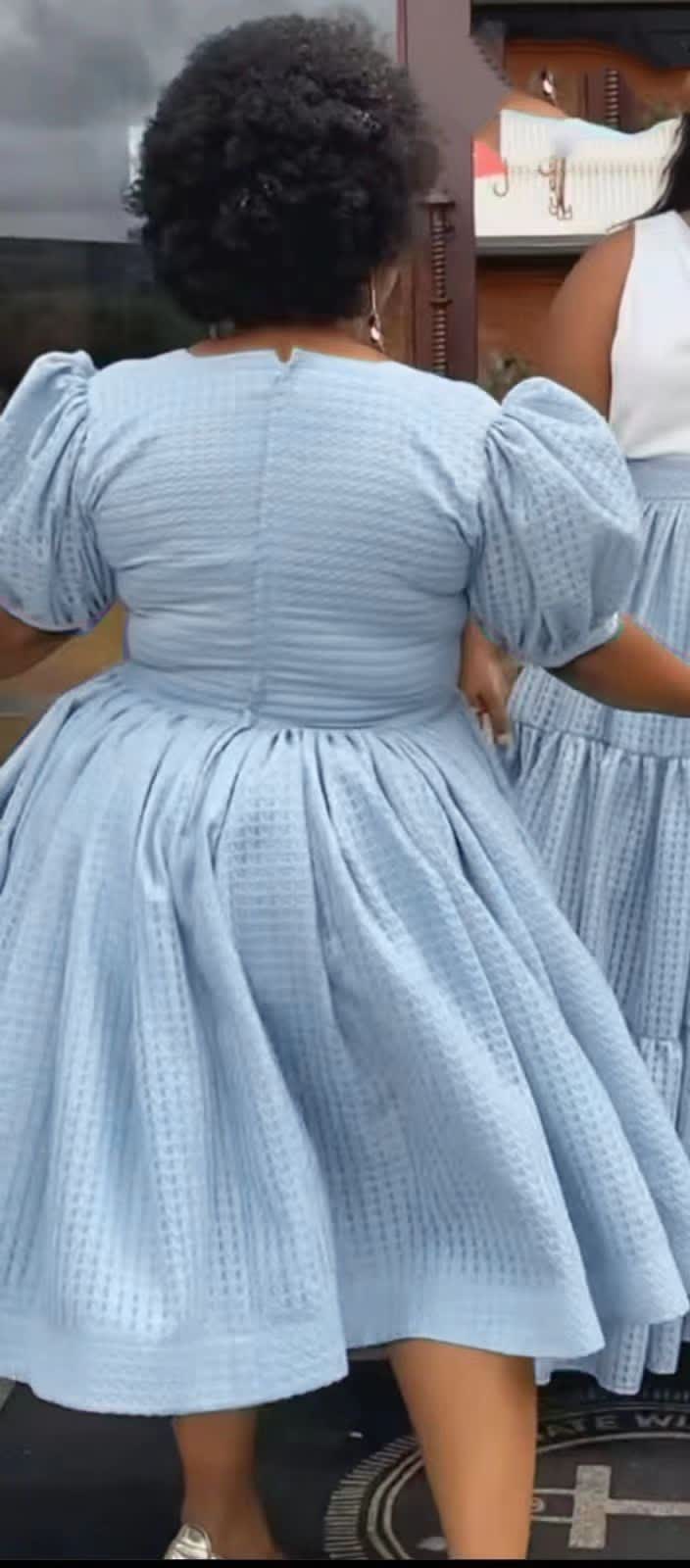 Light blue textured midi dress with puff sleeves and gathered waist, flared skirt (back).