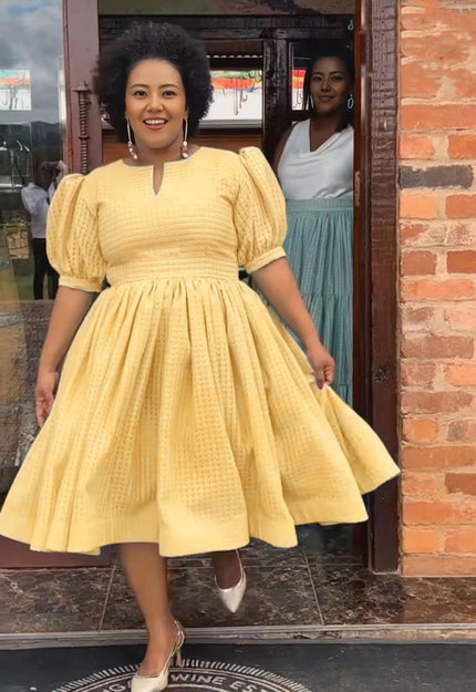 Yellow textured midi dress with puff sleeves and gathered waist, flared skirt.