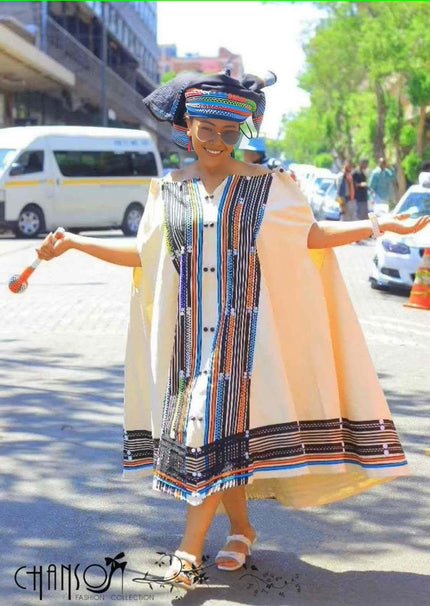 Embroidered cape dress with multicolor striped front and button placket, sleeveless.
