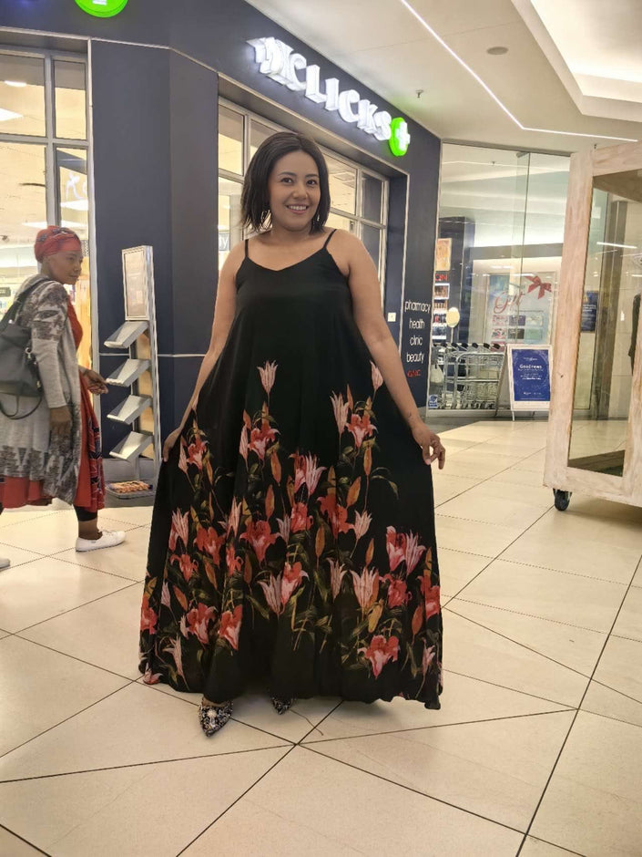 Sleeveless black maxi dress with flared floral skirt and spaghetti straps