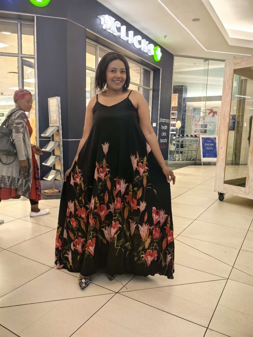 Sleeveless black maxi dress with flared floral skirt and spaghetti straps
