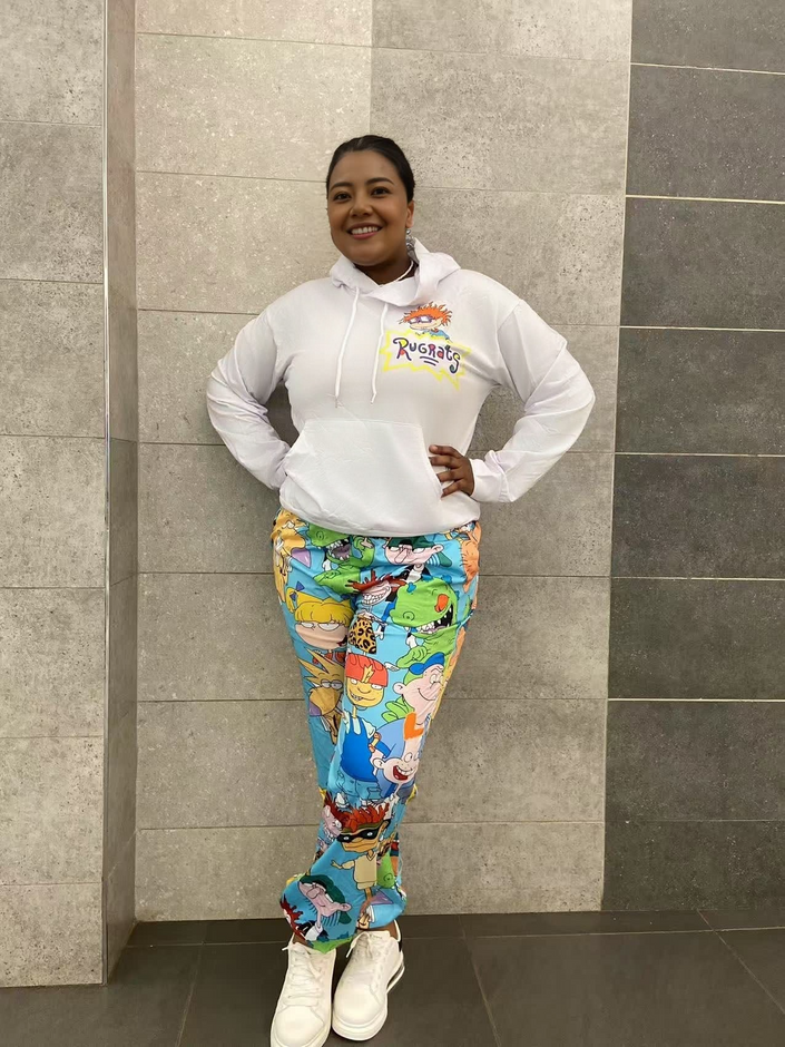 White cartoon hoodie set with yellow-green character-print pants and white sneakers.