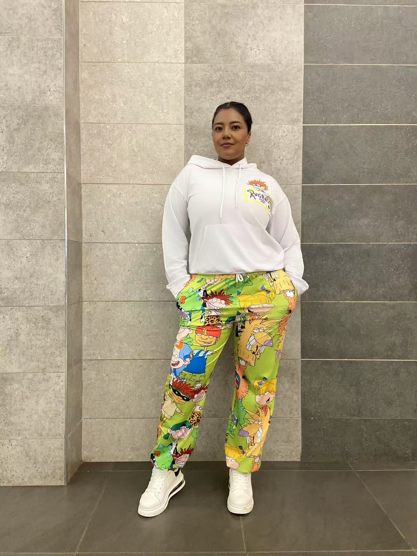 White cartoon hoodie set with green character-print pants, drawstring hood and front pocket.