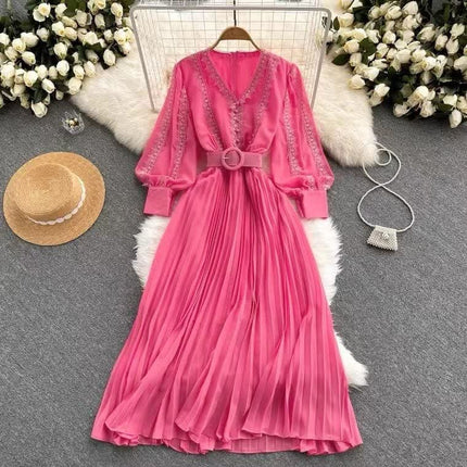 Pink pleated maxi dress with V-neck, long sleeves, and waist belt detail