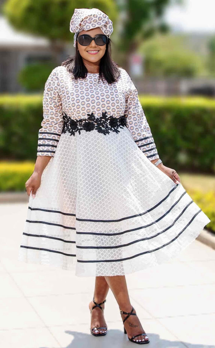 White traditional midi dress with long sleeves, lace stripe trim, and circular pattern bodice.