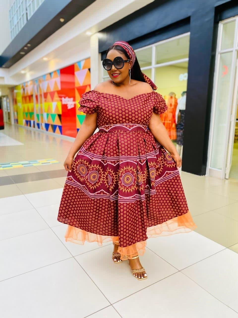 Brown midi dress with off-shoulder ruffle neckline and circular motif skirt
