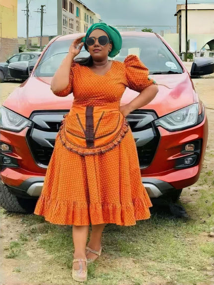 Orange puff-sleeve midi dress with patterned bodice, waist tie, and tiered skirt