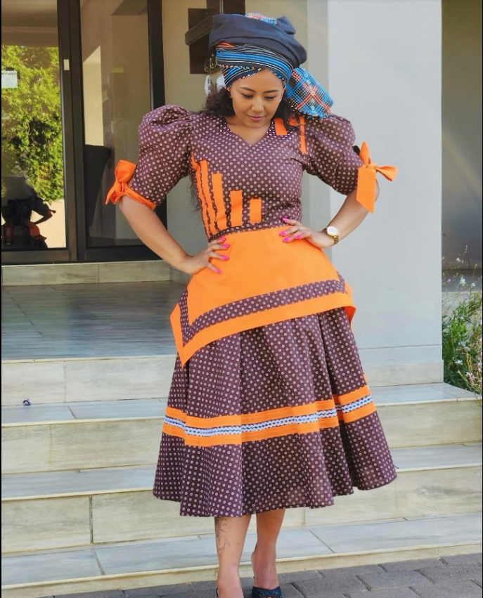 Purple polka-dot midi dress with puff sleeves, orange bows, and striped trim