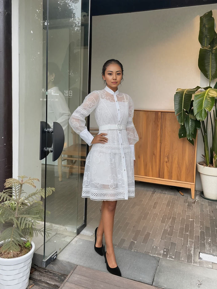 White layered lace mini dress with long puff sleeves, button front, and fitted belt