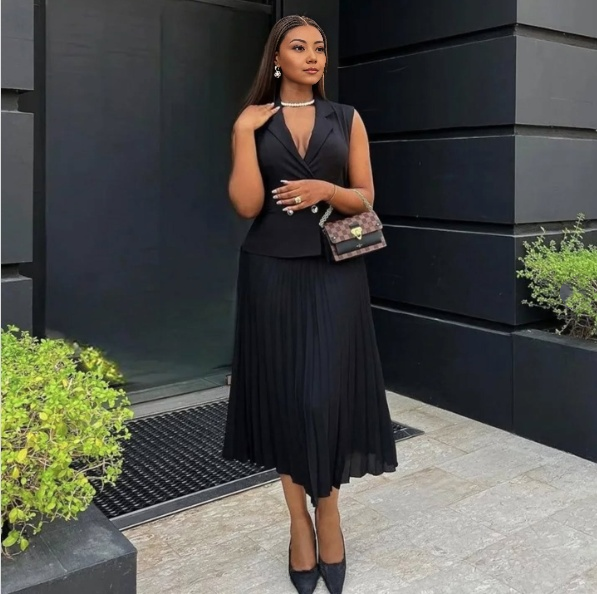 Black sleeveless belted blazer with pleated midi skirt