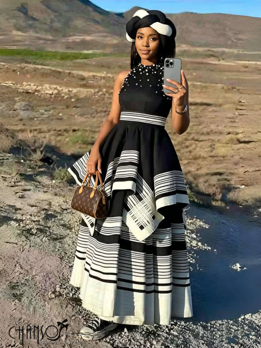 Black beaded maxi dress with high neck, sleeveless; layered black-and-white striped skirt