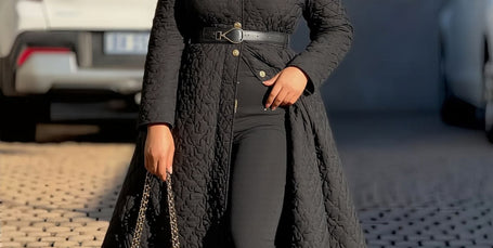 Black quilted A-line women’s coat with collar, belted waist, button front.