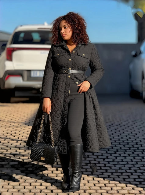Black quilted A-line women’s coat with collar, belted waist, button front.