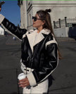 Shearling biker jacket in black with zip front and white fleece trim, belted cuffs