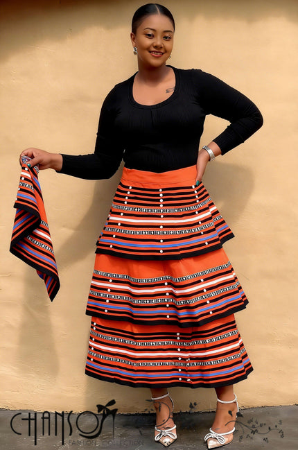 African maxi skirt set: black long-sleeve top with orange striped tiered maxi skirt