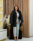 Black plush fur coat with puffy sleeves, open front, mid-length.