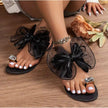 Black women's flat sandals with oversized sheer bow and crystal toe rings